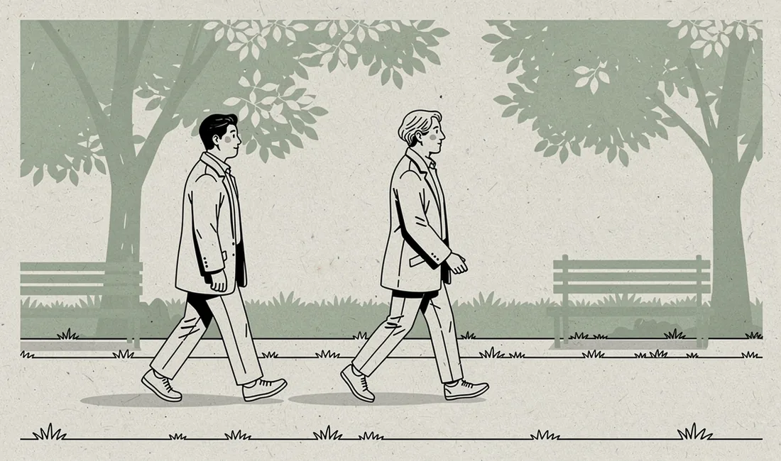 Two adults walking along a level park path beneath leafy trees